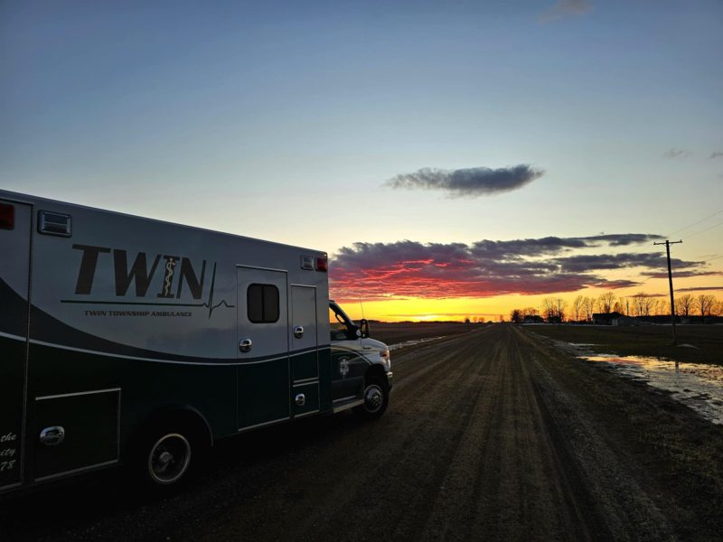 Ambulance #175 overlooking a dirt road with a sunset in background